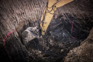 Construction Excavation Site. Excavator Digging Inside Large Ground Hole.